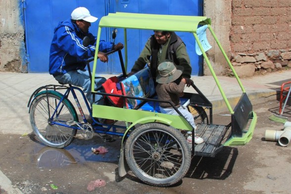 three people crowded around an old lime green tricycle taxi in puno peru