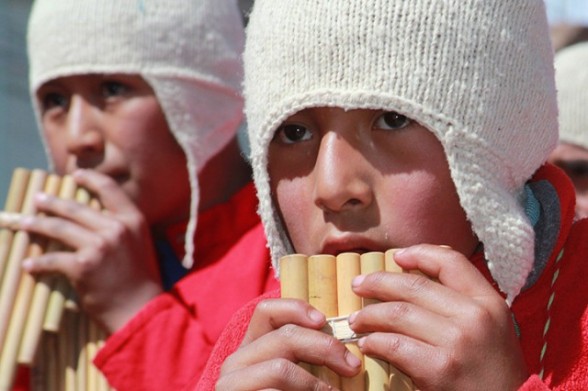 two boys in white hats and red shirts playing the flute