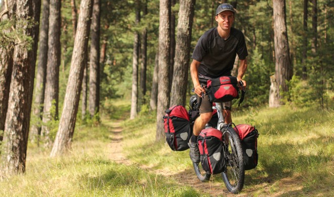 Happy man on bike riding through forest