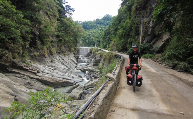 young man bicycle touring downhill on jungle road in taiwan