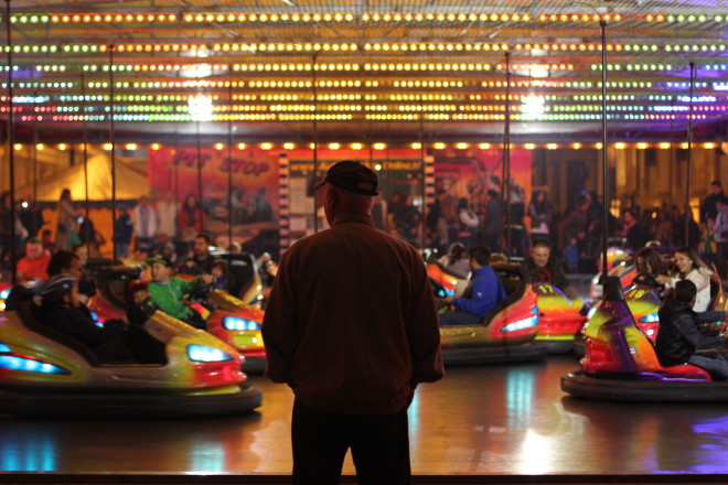 old man watching younger people driving bumper cars
