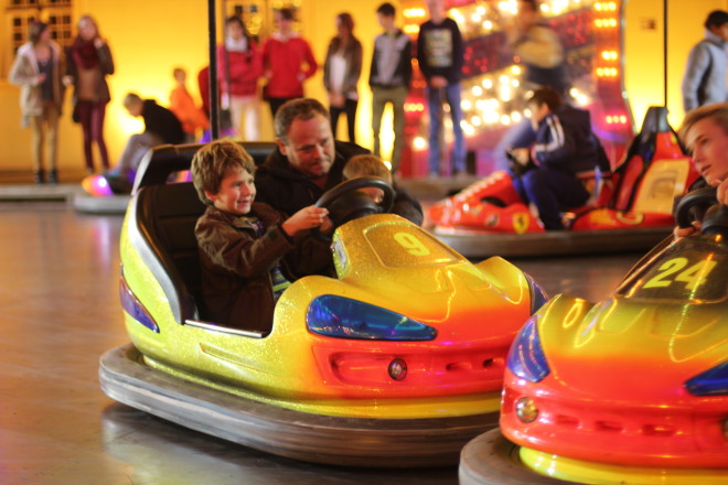 father and son struggling to drive bumper car together