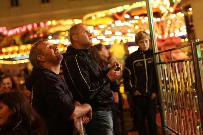 two grown men with young son looking at festival lights and ride