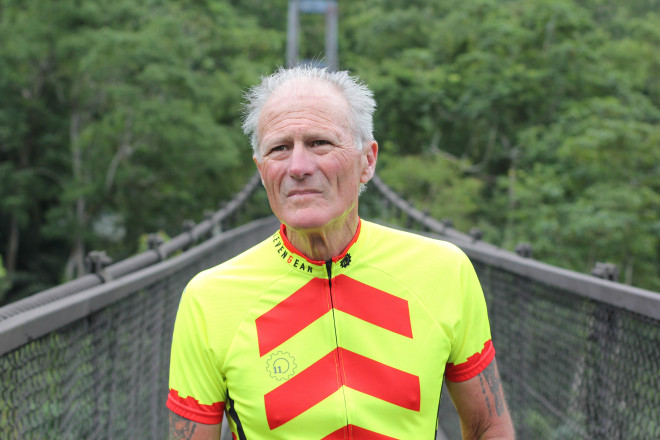 white haired man in bright neon yellow and red cycling jersey