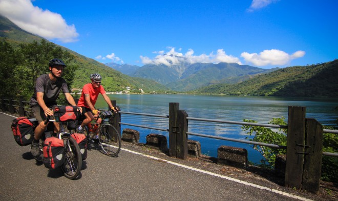 two bicycle tourists riding past liyu lake in taiwan