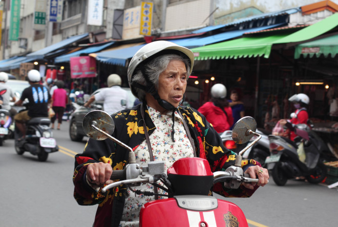 old taiwan woman riding a bright red motor scooter