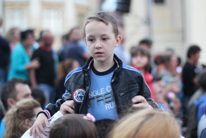 boy in blue shirt above a crowd of people