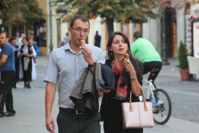 man and woman walking down street and eating ice cream cones