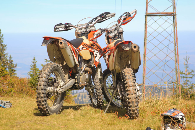 two orange ktm motorcycles leaning up against one another