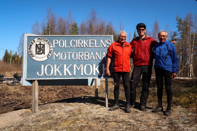 Three men stand at the Polar Circle in Jokkmokk, Sweden