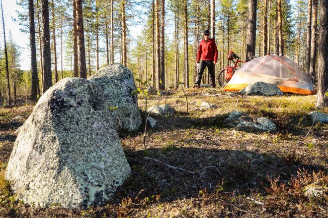 Forest stones greet bicycle tourist pitching tent