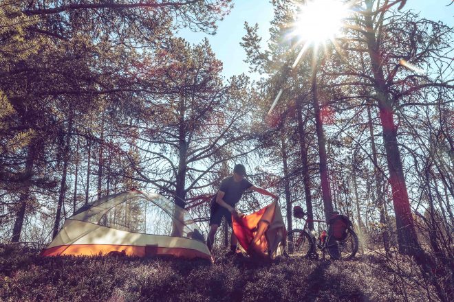 camper pitching tent in sunny forest in finland