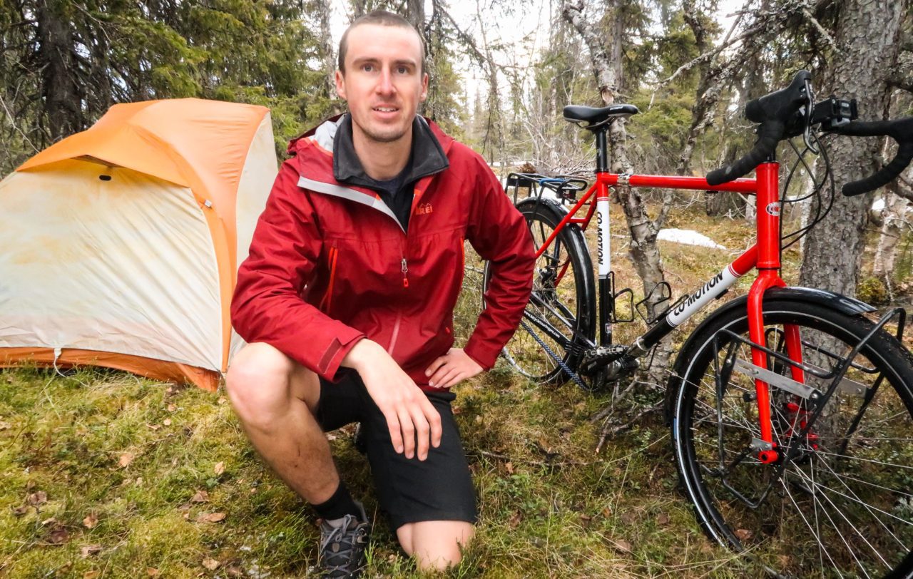 Darren Alff kneeling next to his Big Agnes Copper Spur UL 1 tent and Co-Motion Cycles Siskiyou touring bicycle in Sweden