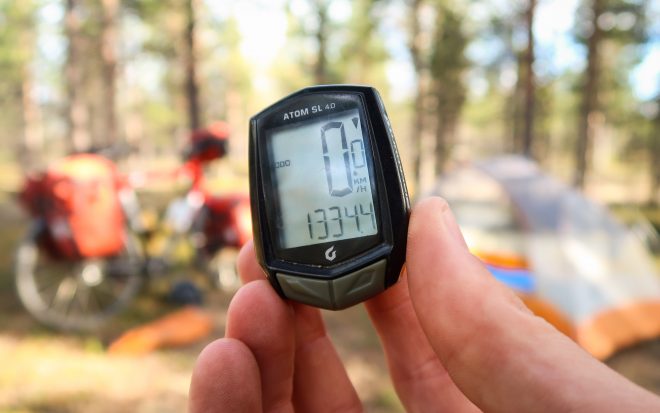 Blackburn bicycle odometer showing 1334 kilometers with a tent and bicycle out of focus in the background