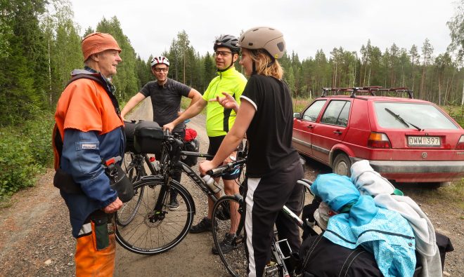 Old lumber worker talks with group of bicycle tourists