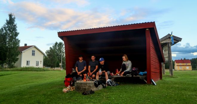Four bicycle tourists sit inside free shelter in northern Sweden