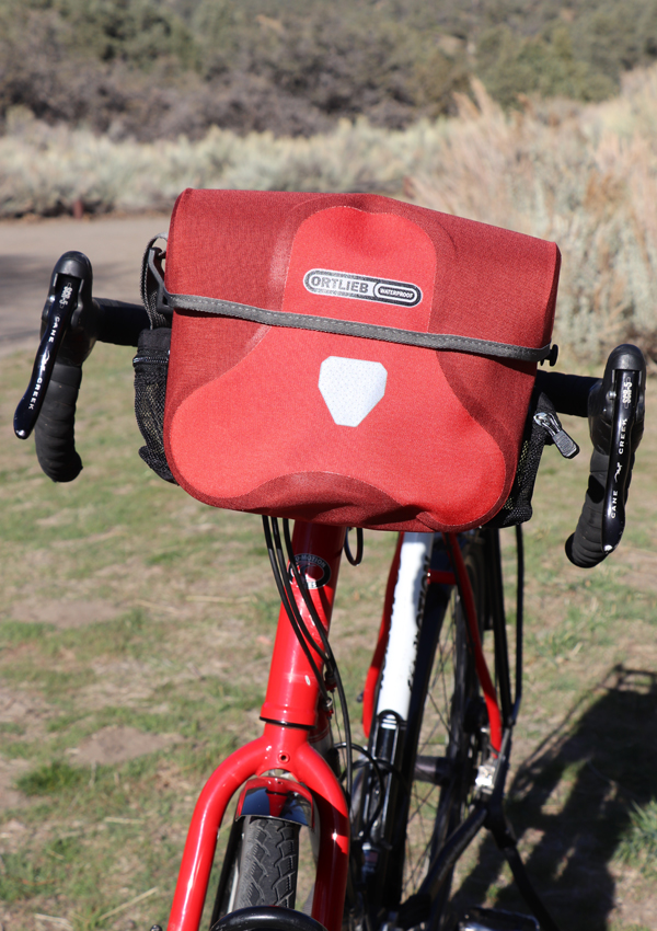 Red Ortlieb Ultimate 6 7 liter waterproof handlebar bag on touring bicycle